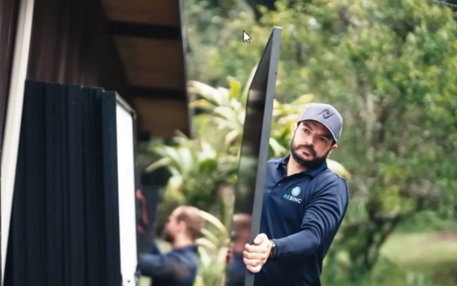 A RESINC team member carries a solar panel during an installation.